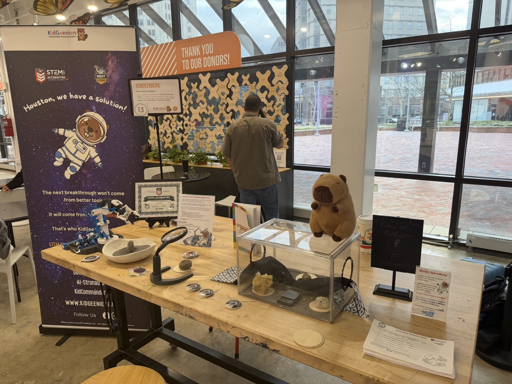KidGeeniers event station with banner, robotic arm, and Mission SpaceRocks materials