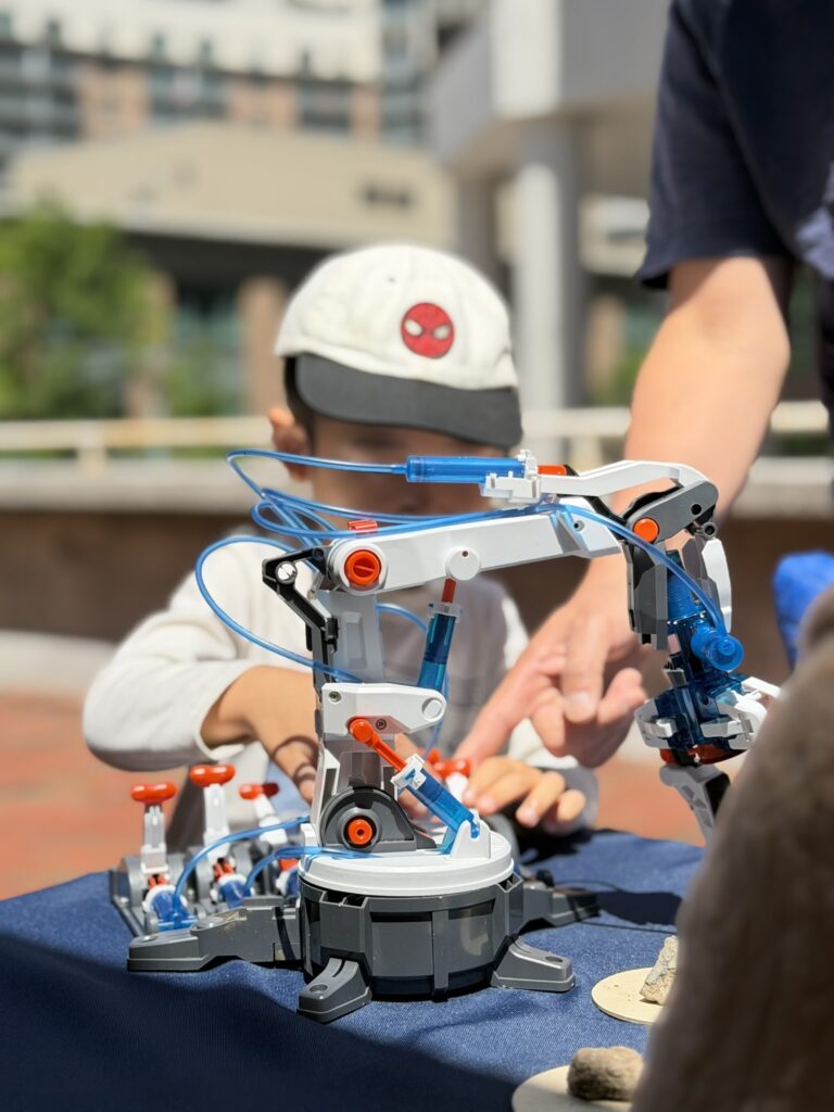 Child operating a hydraulic robotic arm at a KidGeeniers event